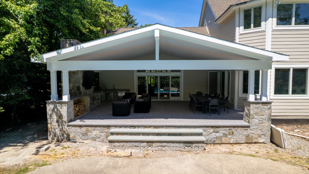 Inspiration pour une grande terrasse arrière design avec une cuisine d'été, du carrelage et une extension de toiture.