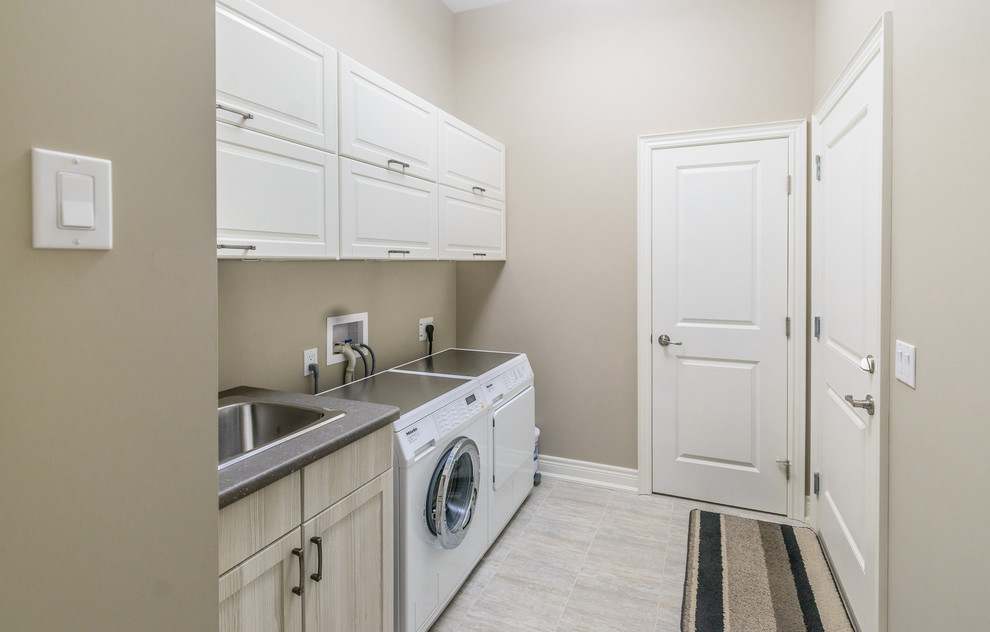 Design ideas for a mid-sized transitional single-wall utility room in Toronto with an undermount sink, recessed-panel cabinets, white cabinets, laminate benchtops, beige walls, ceramic floors and a side-by-side washer and dryer.