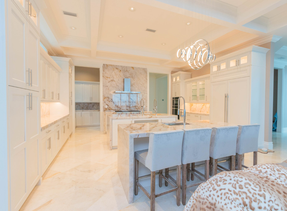 Example of a huge transitional u-shaped marble floor and white floor open concept kitchen design with an undermount sink, flat-panel cabinets, white cabinets, quartzite countertops, white backsplash, stone slab backsplash and two islands