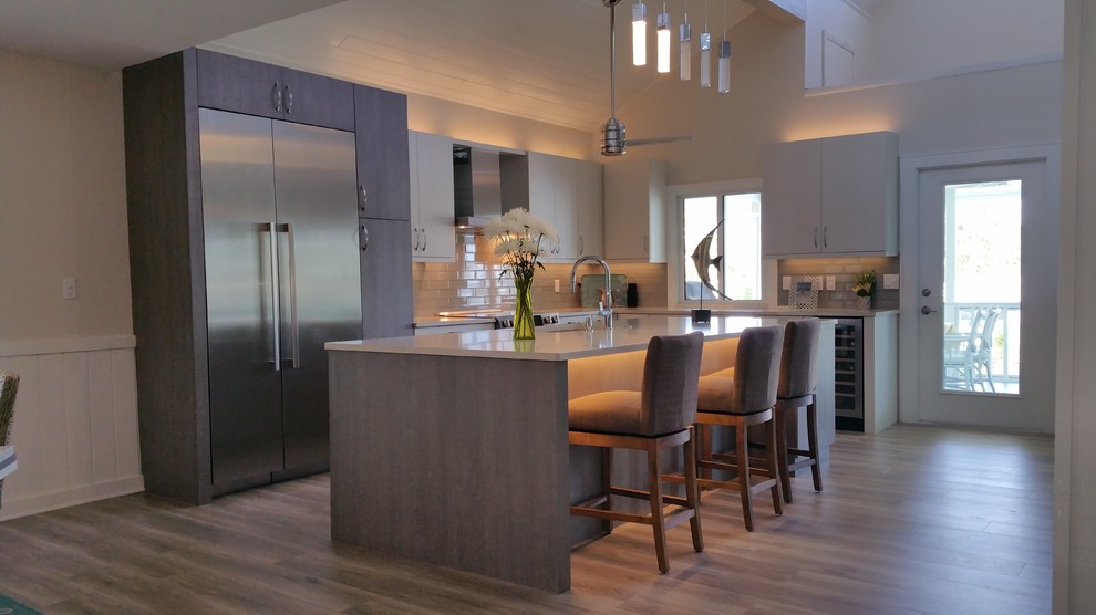 This is an example of a mid-sized contemporary l-shaped eat-in kitchen in Tampa with white splashback, glass tile splashback, stainless steel appliances, light hardwood floors, with island, an undermount sink, flat-panel cabinets, medium wood cabinets, quartzite benchtops and beige floor.