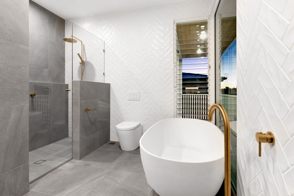Cette photo montre une grande douche en alcôve principale scandinave avec une baignoire indépendante, WC à poser, un mur blanc, un sol en carrelage de céramique, un sol gris et une cabine de douche à porte battante.