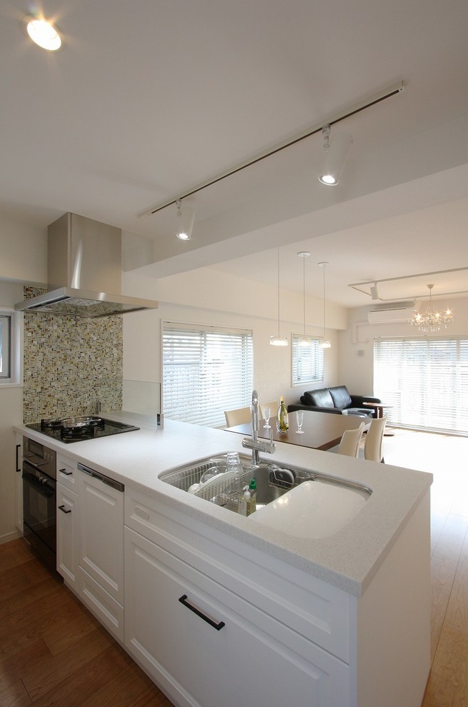This is an example of a contemporary kitchen in Tokyo with a single-bowl sink, recessed-panel cabinets, white cabinets, with island and brown floor.