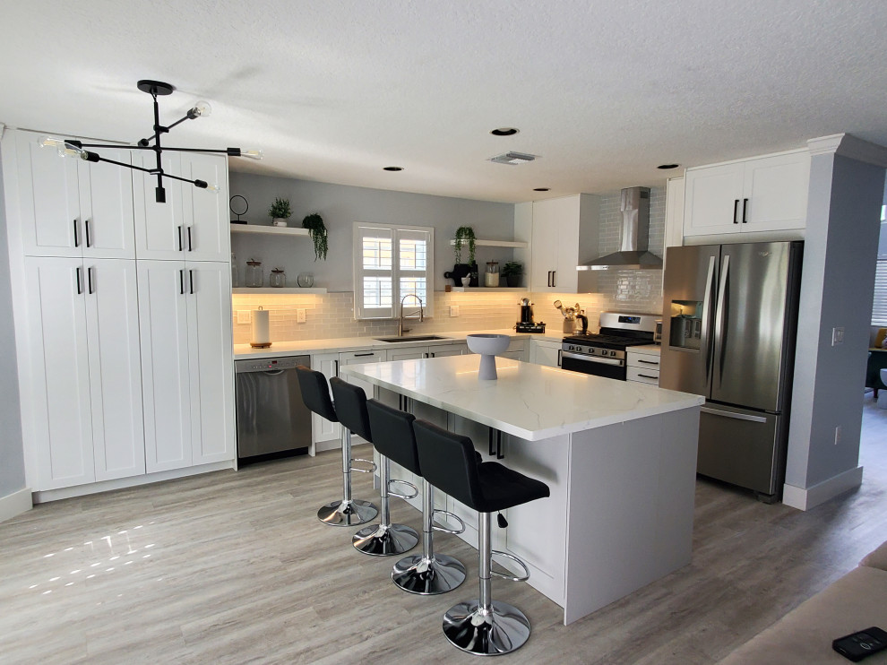 Inspiration for a large transitional l-shaped kitchen pantry remodel in Miami with shaker cabinets, white cabinets, quartz countertops and an island