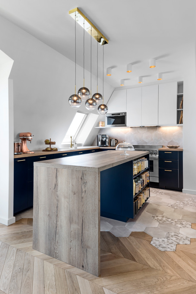Inspiration for a contemporary l-shaped kitchen in Paris with flat-panel cabinets, blue cabinets, wood benchtops, grey splashback, stainless steel appliances, medium hardwood floors, with island, brown floor and beige benchtop.