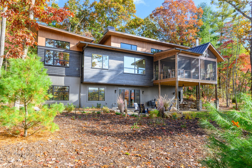 Mountain style black three-story mixed siding house exterior photo with a shed roof and a mixed material roof