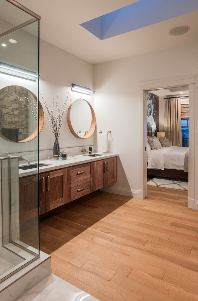 Corner shower - transitional master medium tone wood floor and brown floor corner shower idea in Calgary with medium tone wood cabinets, white walls and an undermount sink