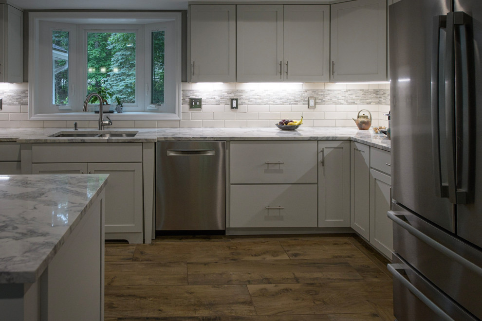 Large contemporary eat-in kitchen in Boston with an undermount sink, shaker cabinets, white cabinets, marble benchtops, white splashback, porcelain splashback, stainless steel appliances, porcelain floors, with island, brown floor, white benchtop and coffered.