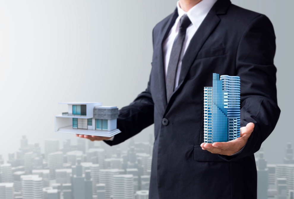 person holding two types of buildings of commercial development and residential development.