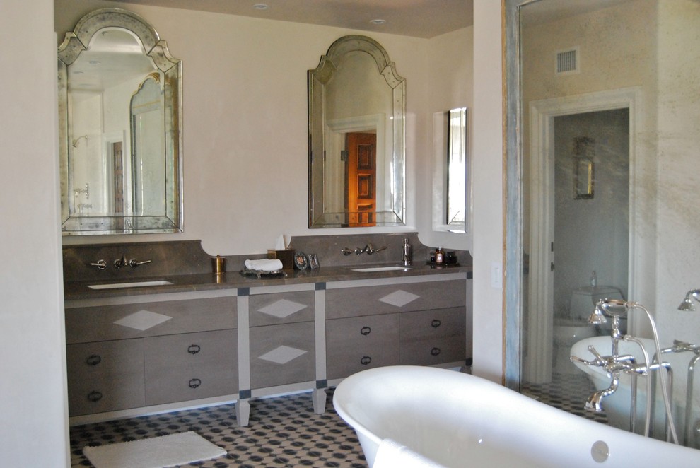 Photo of a mediterranean master bathroom in Los Angeles with an undermount sink, grey cabinets, a freestanding tub, cement tile and beige walls.