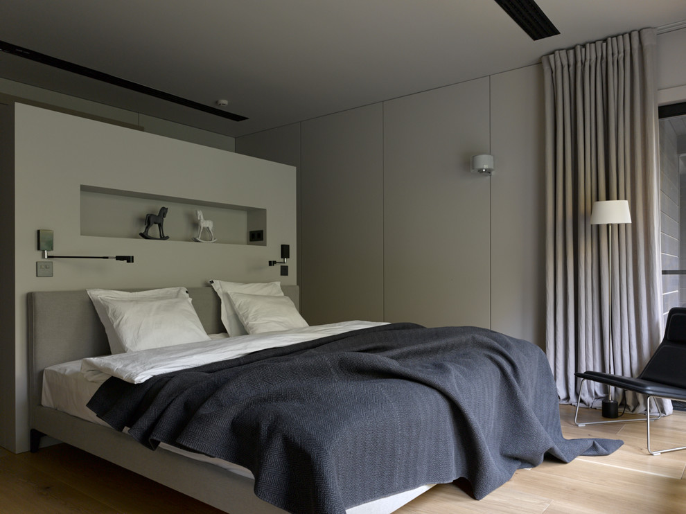 This is an example of a contemporary master bedroom in Moscow with light hardwood floors and beige floor.