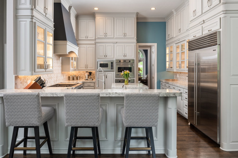 Design ideas for a mid-sized traditional u-shaped kitchen in Dallas with with island, raised-panel cabinets, beige cabinets, beige splashback, stainless steel appliances, dark hardwood floors, brown floor and multi-coloured benchtop.