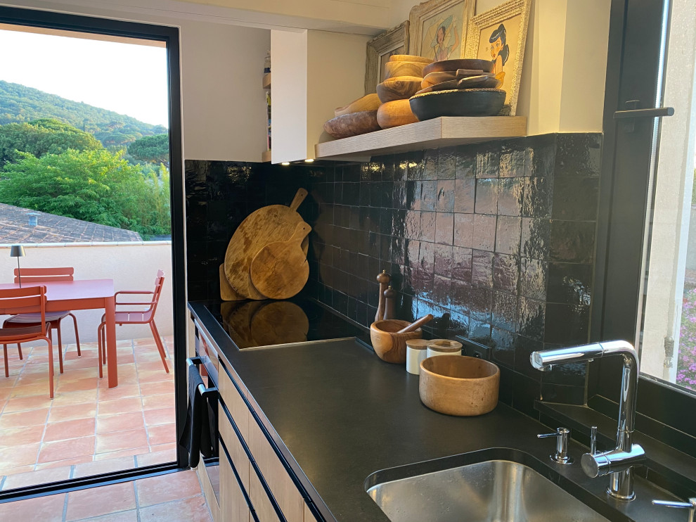 This is an example of a small contemporary galley open plan kitchen in Other with an undermount sink, beaded inset cabinets, white cabinets, granite benchtops, black splashback, porcelain splashback, white appliances, terra-cotta floors, no island, orange floor, black benchtop and exposed beam.