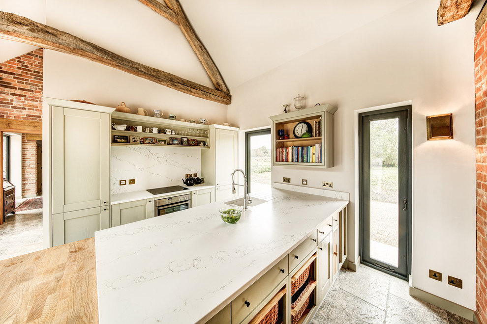 Photo of a country kitchen in Hampshire with shaker cabinets, green cabinets, white splashback and white benchtop.