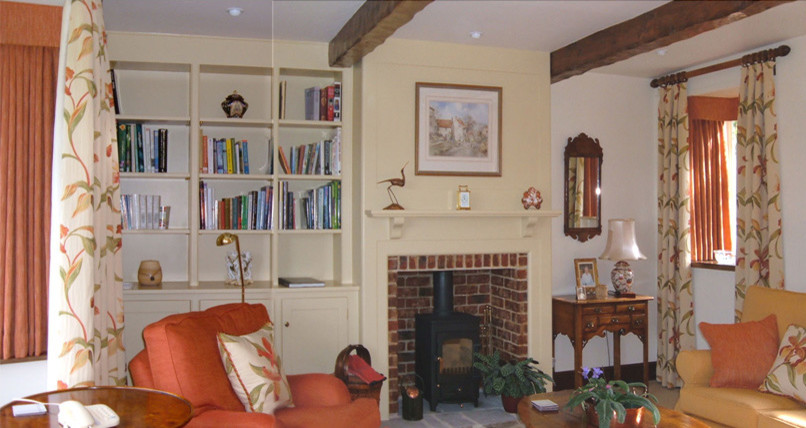 Photo of a medium sized classic enclosed living room with a reading nook, yellow walls, carpet, a wood burning stove, a brick fireplace surround and a freestanding tv.