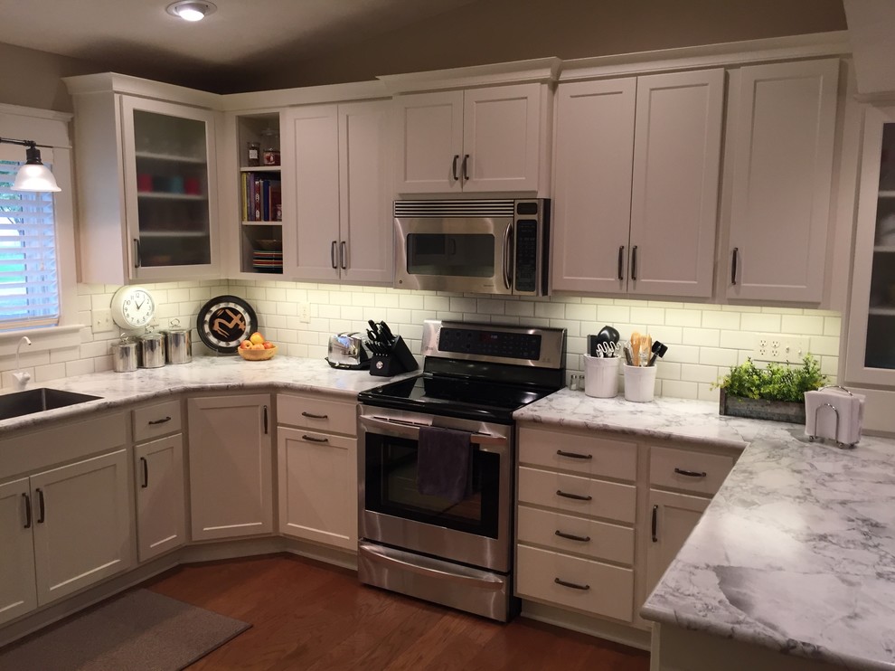 Mid-sized transitional u-shaped medium tone wood floor eat-in kitchen photo with an integrated sink, shaker cabinets, white cabinets, laminate countertops, white backsplash, subway tile backsplash, stainless steel appliances and a peninsula