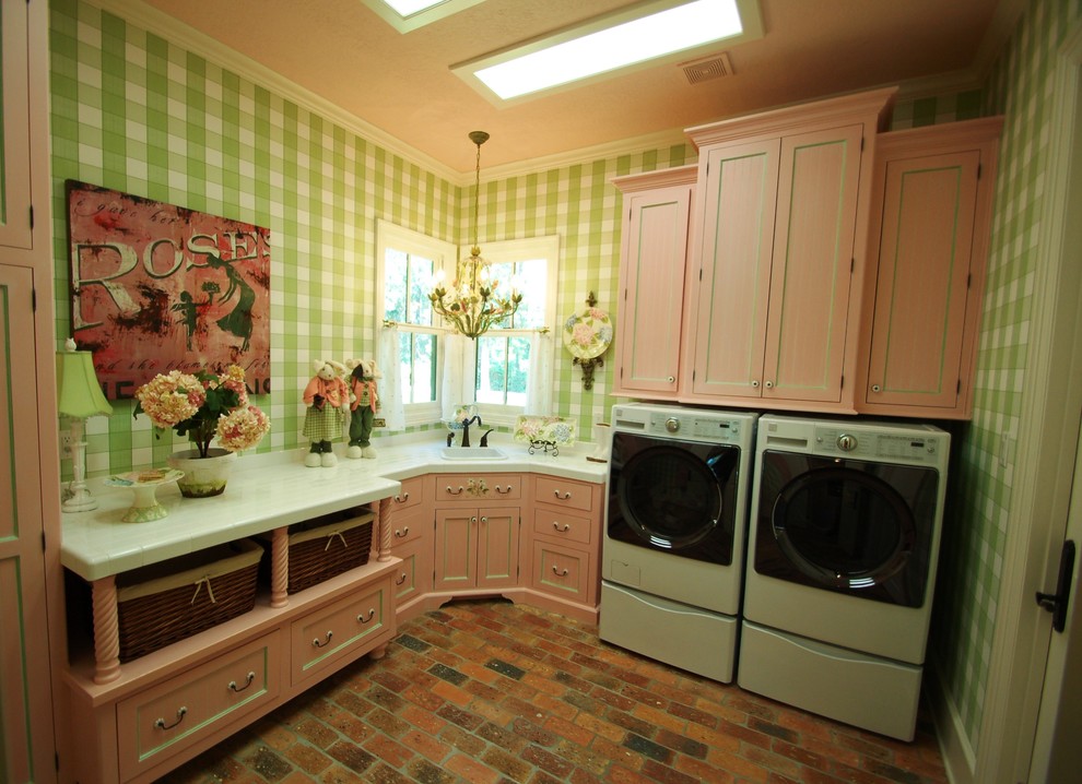 This is an example of a country l-shaped dedicated laundry room in Houston with a drop-in sink, shaker cabinets, distressed cabinets, marble benchtops, green walls, brick floors and a side-by-side washer and dryer.
