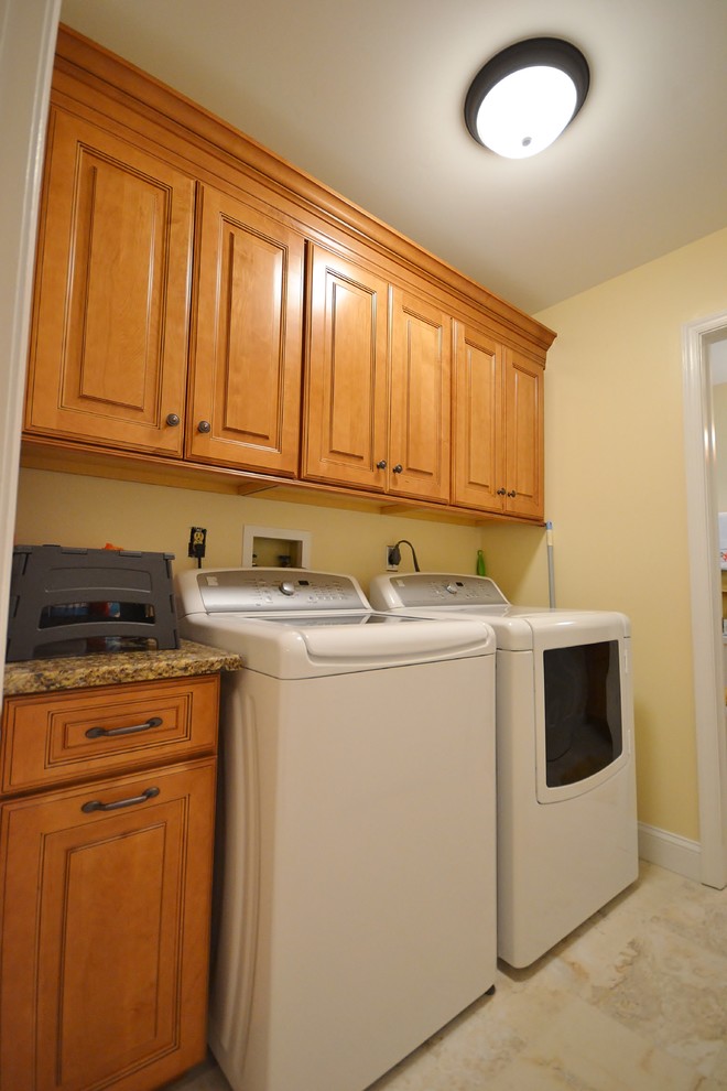 This is an example of a mid-sized transitional single-wall utility room in Philadelphia with raised-panel cabinets, light wood cabinets, quartz benchtops, beige walls, ceramic floors and a side-by-side washer and dryer.