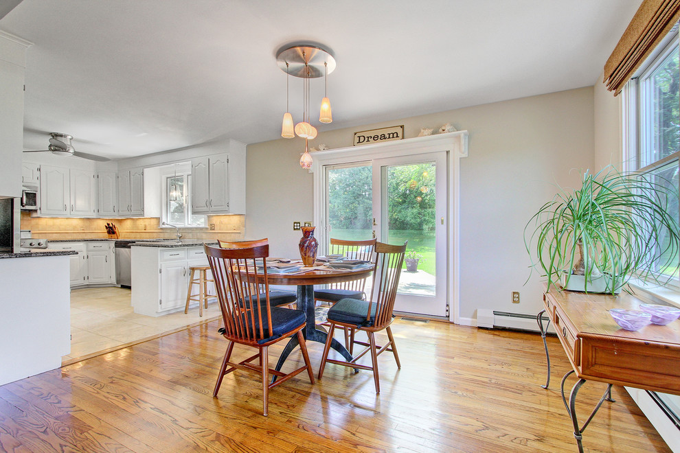 Open concept kitchen - mid-sized transitional u-shaped medium tone wood floor open concept kitchen idea in New York with an undermount sink, raised-panel cabinets, white cabinets, granite countertops, beige backsplash, ceramic backsplash, stainless steel appliances and an island