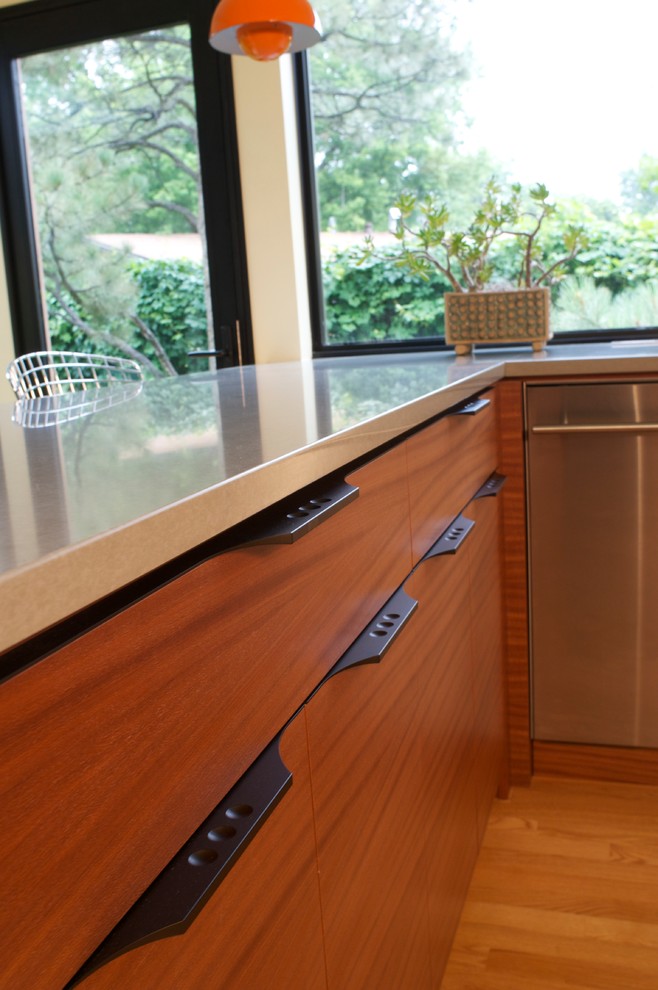 This is an example of a mid-sized midcentury u-shaped kitchen in Denver with a double-bowl sink, flat-panel cabinets, medium wood cabinets, quartz benchtops, yellow splashback, stainless steel appliances and light hardwood floors.