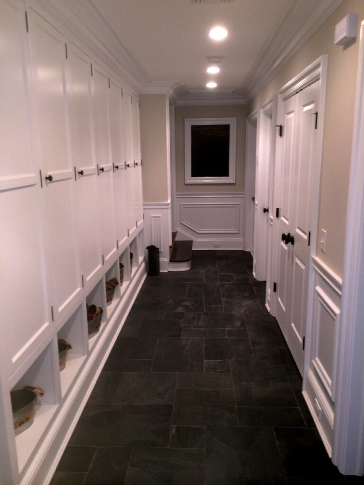 Inspiration for a mid-sized galley dedicated laundry room in New York with recessed-panel cabinets, white cabinets, beige walls and slate floors.