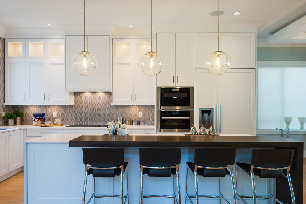 Mid-sized transitional l-shaped light wood floor and beige floor open concept kitchen photo in Vancouver with an undermount sink, shaker cabinets, white cabinets, quartz countertops, gray backsplash, mosaic tile backsplash, paneled appliances, an island and gray countertops
