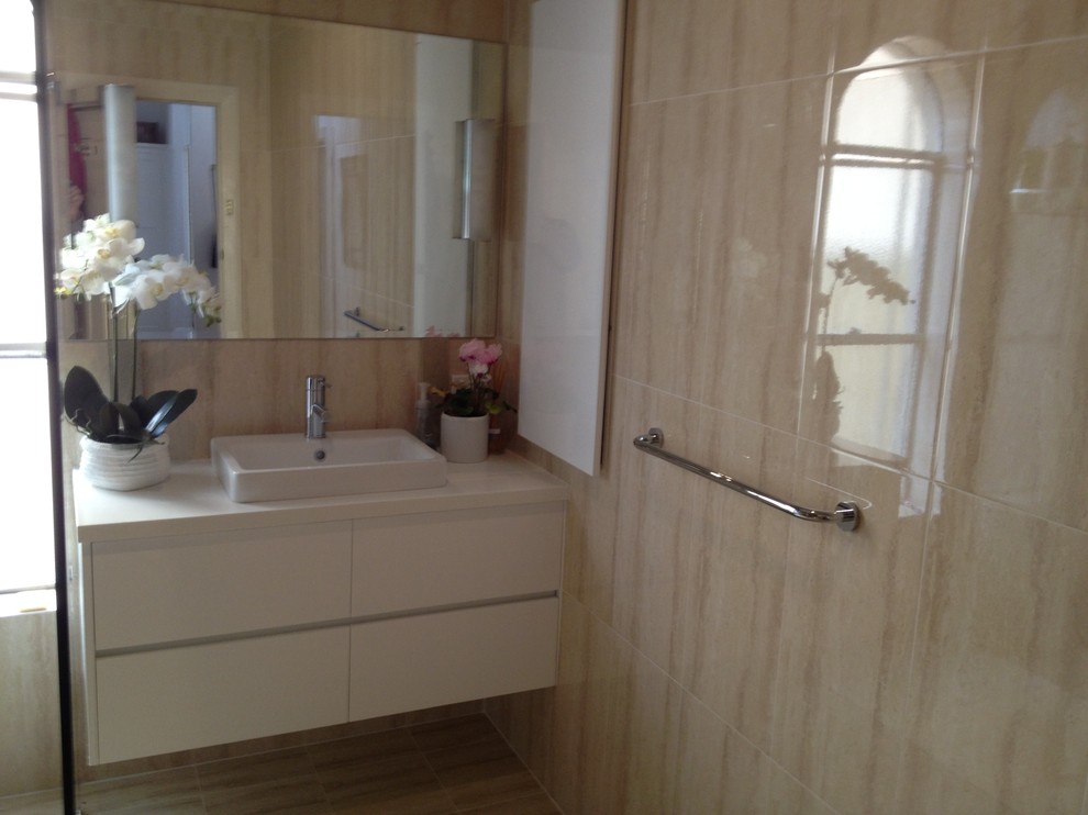 Photo of a mid-sized modern bathroom in Perth with a drop-in sink, white cabinets, granite benchtops, a one-piece toilet, beige tile, ceramic tile, beige walls and ceramic floors.