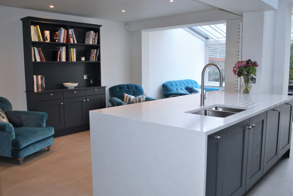 Inspiration for a large modern single-wall eat-in kitchen in London with an integrated sink, shaker cabinets, blue cabinets, quartzite benchtops, white splashback, stone slab splashback, stainless steel appliances, porcelain floors, with island, grey floor and white benchtop.