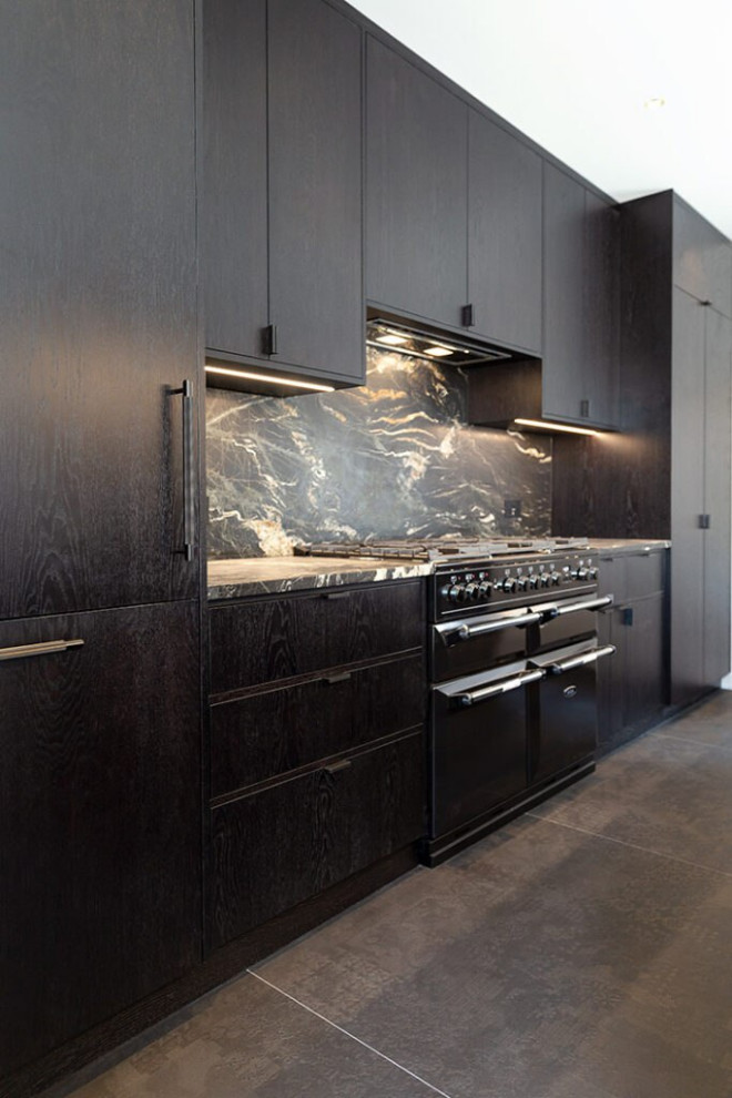 Bild på ett stort skandinaviskt svart linjärt svart kök och matrum, med en enkel diskho, luckor med profilerade fronter, svarta skåp, bänkskiva i akrylsten, svart stänkskydd, svarta vitvaror, klinkergolv i keramik, en köksö, beiget golv och stänkskydd i marmor