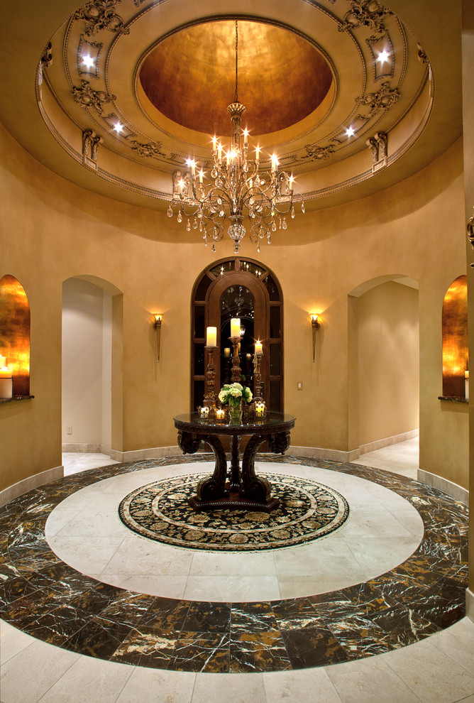 This is an example of an expansive traditional foyer in Phoenix with beige walls, limestone floors, a single front door and a dark wood front door.