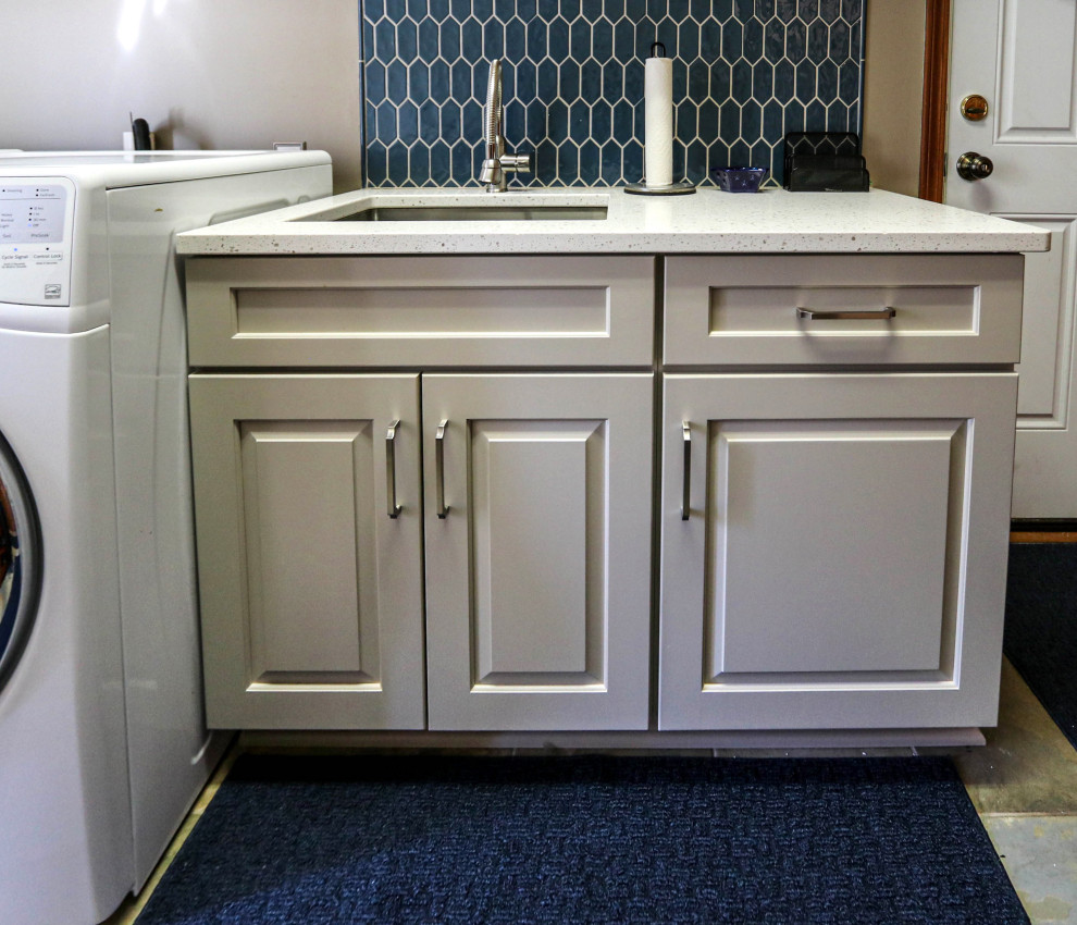 クリーブランドにあるお手頃価格の小さなトランジショナルスタイルのおしゃれな洗濯室 (I型、アンダーカウンターシンク、レイズドパネル扉のキャビネット、白いキャビネット、クオーツストーンカウンター、青いキッチンパネル、セメントタイルのキッチンパネル、グレーの壁、左右配置の洗濯機・乾燥機、白いキッチンカウンター) の写真