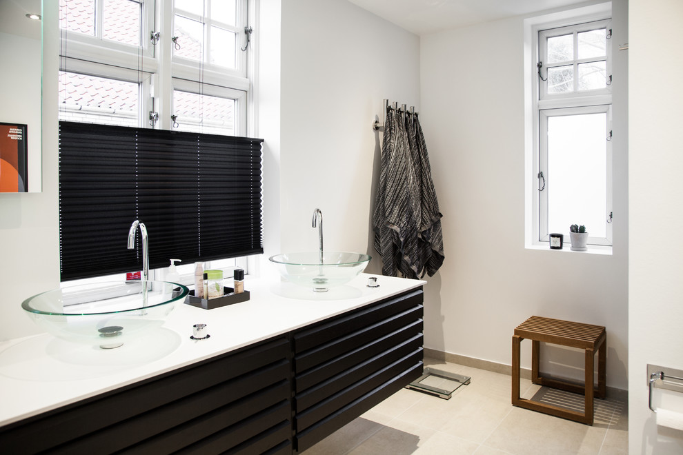 Inspiration for a mid-sized scandinavian bathroom in Odense with black cabinets, white walls, a vessel sink, beige floor and white benchtops.
