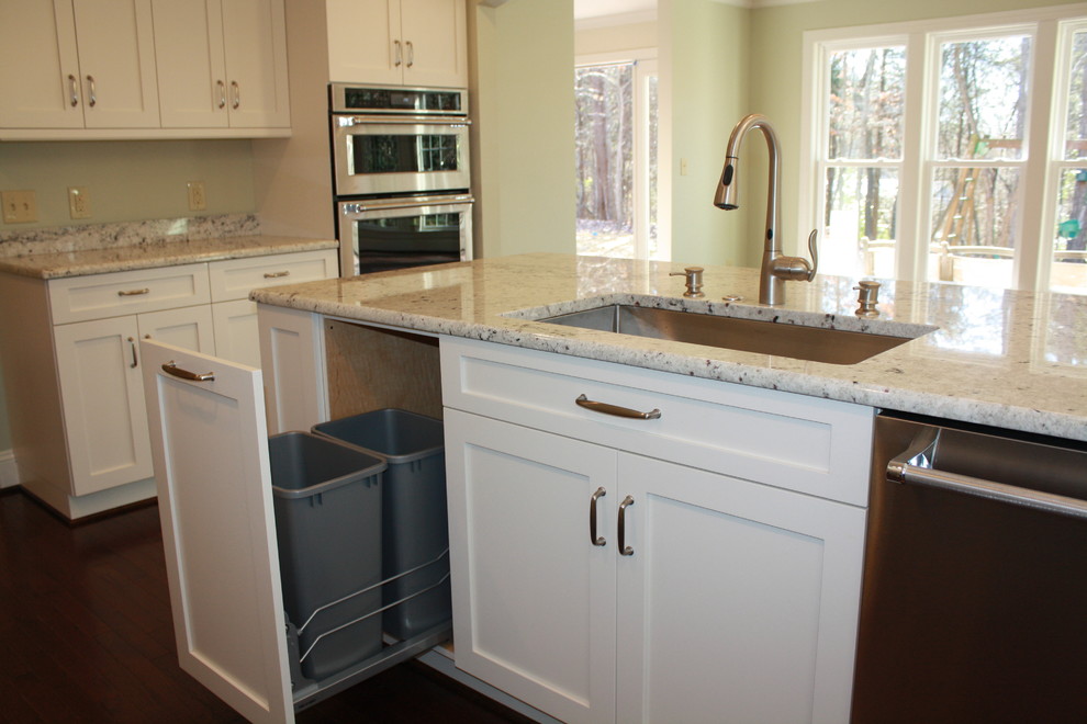 Example of a mid-sized transitional u-shaped dark wood floor eat-in kitchen design in Charlotte with an undermount sink, recessed-panel cabinets, white cabinets, granite countertops, stainless steel appliances and an island