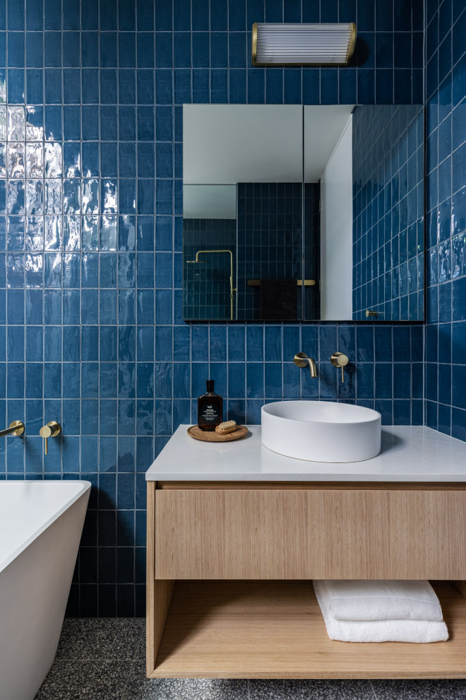Источник вдохновения для домашнего уюта: маленькая главная ванная комната в современном стиле с открытыми фасадами, светлыми деревянными фасадами, отдельно стоящей ванной, открытым душем, синей плиткой, керамической плиткой, синими стенами, полом из терраццо, столешницей из искусственного кварца, серым полом, открытым душем, белой столешницей, тумбой под одну раковину и подвесной тумбой для на участке и в саду