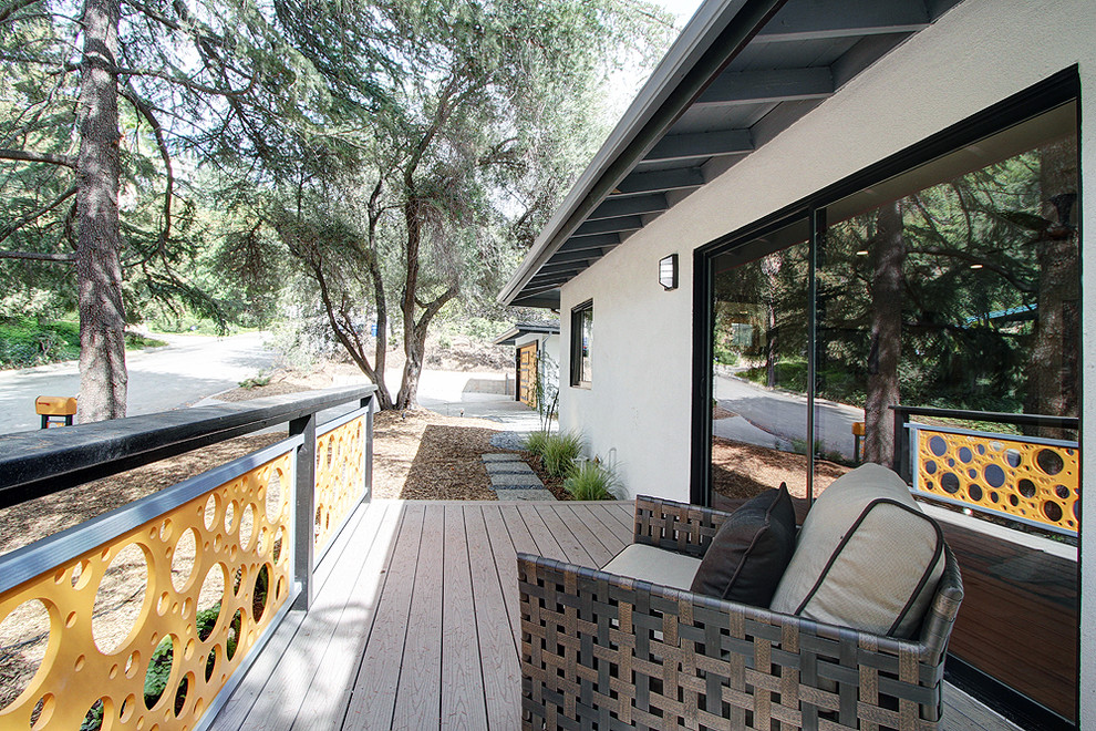 This is an example of a midcentury backyard patio in Los Angeles with decking and a roof extension.