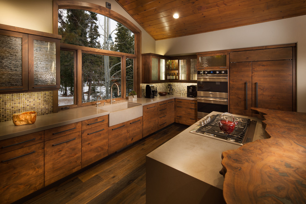 Design ideas for a country l-shaped kitchen in Sacramento with a farmhouse sink, flat-panel cabinets, dark wood cabinets, mosaic tile splashback and panelled appliances.
