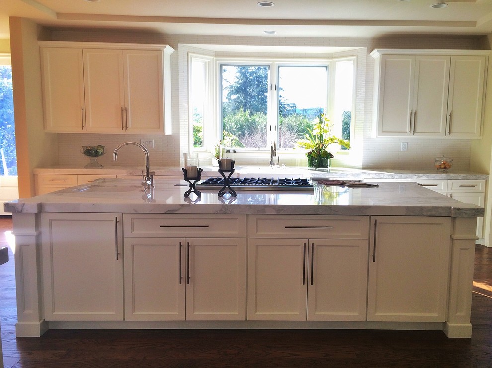 Large country u-shaped eat-in kitchen in Los Angeles with a farmhouse sink, beaded inset cabinets, white cabinets, marble benchtops, white splashback, ceramic splashback, stainless steel appliances, dark hardwood floors, with island and brown floor.
