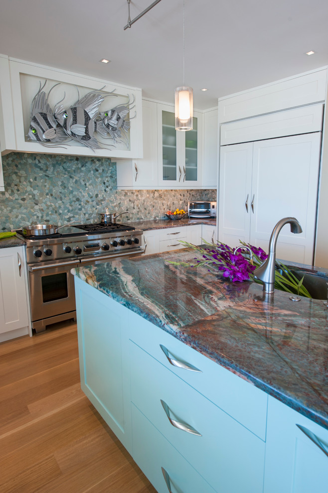 Tropical kitchen in Philadelphia with white cabinets, granite benchtops, multi-coloured splashback, stainless steel appliances and a peninsula.