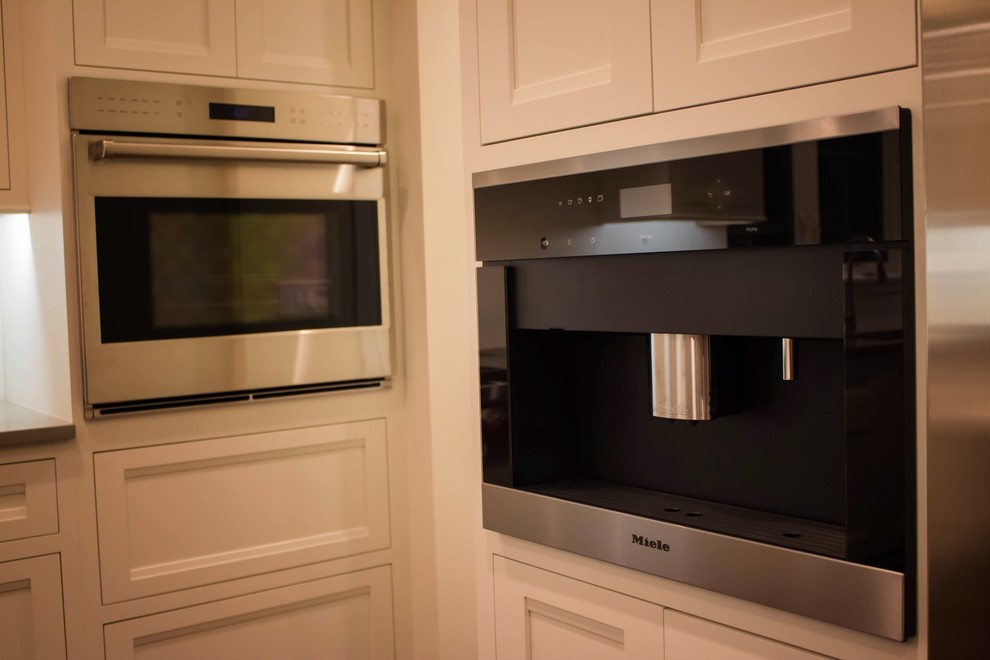 Enclosed kitchen - mid-sized transitional l-shaped dark wood floor enclosed kitchen idea in Chicago with an undermount sink, recessed-panel cabinets, white cabinets, solid surface countertops, white backsplash, porcelain backsplash, stainless steel appliances and an island