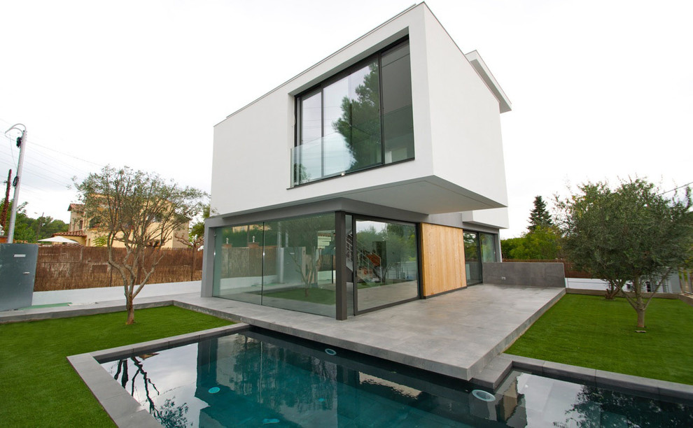 Inspiration for a large contemporary two-storey white exterior in Barcelona with mixed siding and a flat roof.