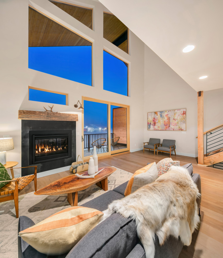 Contemporary open concept living room in Seattle with white walls, light hardwood floors and a corner fireplace.