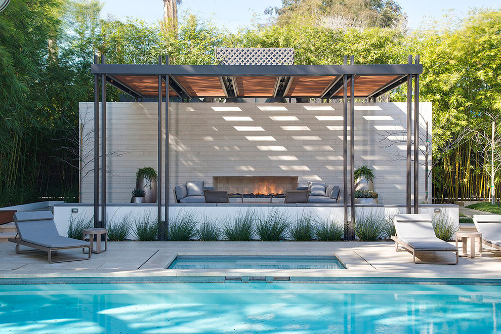 Expansive contemporary backyard rectangular pool in Los Angeles with a pool house and concrete pavers.