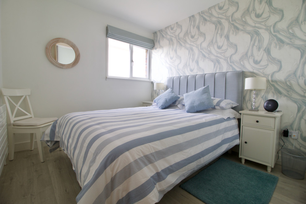 Esempio di una camera degli ospiti stile marinaro di medie dimensioni con pareti blu, pavimento in laminato, pavimento beige e carta da parati
