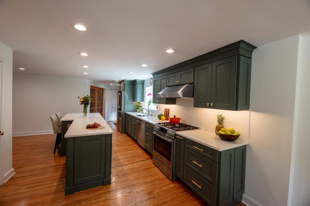 Photo of a small galley eat-in kitchen in Philadelphia with an undermount sink, recessed-panel cabinets, grey cabinets, quartz benchtops, white splashback, porcelain splashback, stainless steel appliances, light hardwood floors, with island, brown floor and white benchtop.