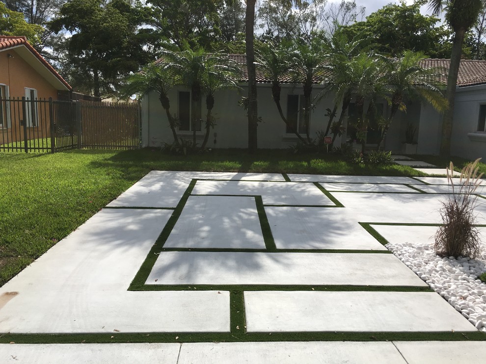 This is an example of a mid-sized contemporary front yard partial sun driveway in Miami with concrete pavers.