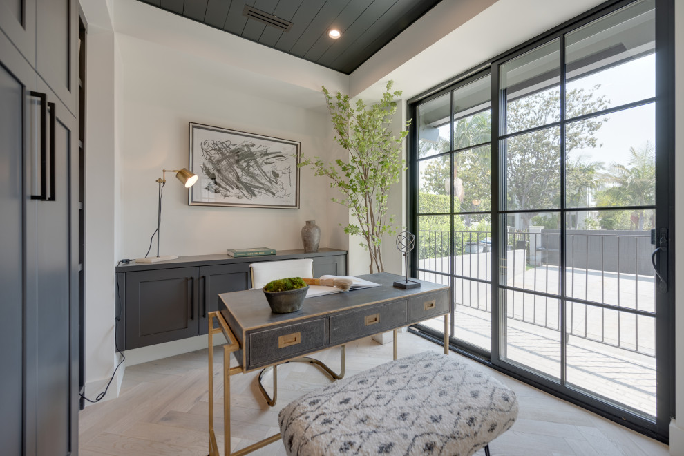 This is an example of a mid-sized country study room in Los Angeles with white walls, light hardwood floors, a standard fireplace, a stone fireplace surround, a freestanding desk and black floor.