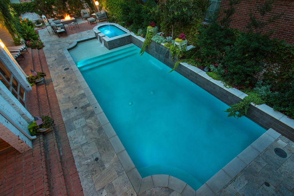 This is an example of a mid-sized traditional backyard rectangular lap pool in Dallas with a water feature and natural stone pavers.
