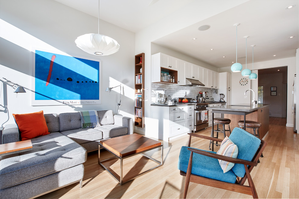 Enclosed kitchen - mid-sized transitional galley light wood floor enclosed kitchen idea in Toronto with a single-bowl sink, shaker cabinets, white cabinets, quartz countertops, white backsplash, porcelain backsplash, stainless steel appliances and an island
