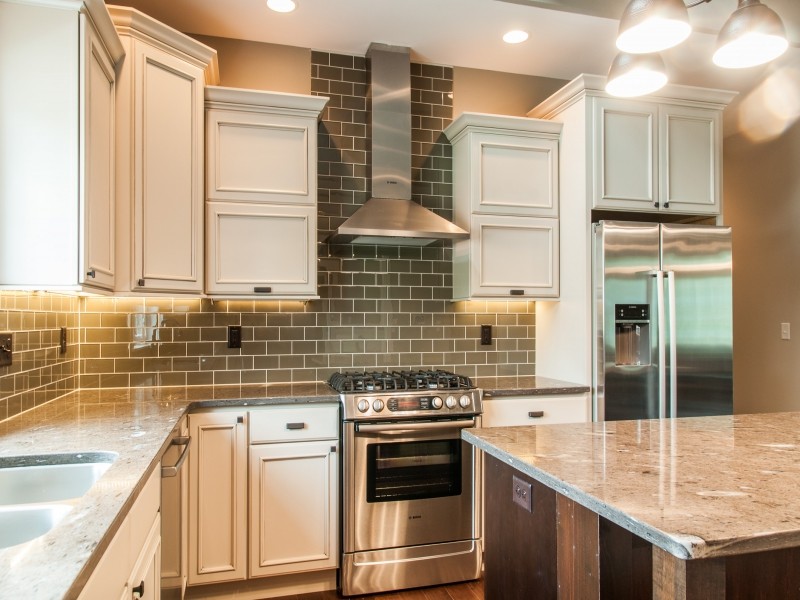Mid-sized transitional medium tone wood floor and brown floor kitchen photo in Cedar Rapids with a double-bowl sink, beaded inset cabinets, white cabinets, granite countertops, brown backsplash, subway tile backsplash, stainless steel appliances and an island