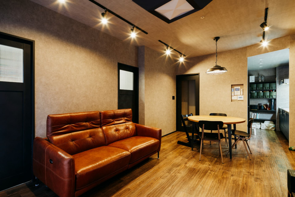 This is an example of an industrial living room in Nagoya with brown walls, a freestanding tv and brown floors.