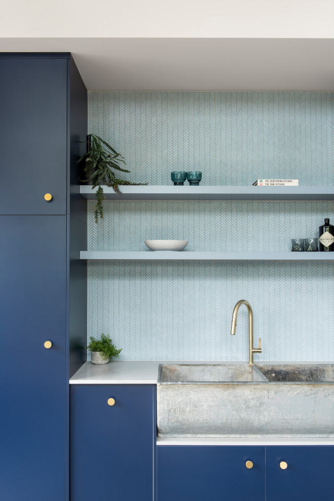 Idéer för ett modernt kök, med en rustik diskho, blå skåp, blått stänkskydd och betonggolv